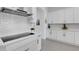 Modern kitchen featuring white cabinets, white subway tile backsplash, and stainless steel range hood at 19337 Cruise Dr, Venice, FL 34292