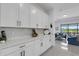 Kitchen with sleek white cabinets, quartz countertops, and a view of the bright living area at 19337 Cruise Dr, Venice, FL 34292