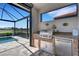 Covered outdoor kitchen features a built-in grill, mini fridge, and stone accents overlooking the pool at 19337 Cruise Dr, Venice, FL 34292