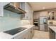 Modern kitchen featuring a stainless steel hood, flat cooktop, subway tile backsplash, and stainless steel appliances at 20660 Ovid Ln, Venice, FL 34293