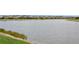 A wide lakefront view framed by green grass showing calm waters and distant lakeside homes at 20660 Ovid Ln, Venice, FL 34293