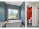 A standalone bathtub with a filler and red water closet, complemented by vibrant wallpaper, creates a striking bathroom aesthetic at 2092 Timucua Trl, Nokomis, FL 34275