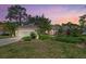 Charming single-story home with well-manicured landscaping and a tile roof at sunset at 2092 Timucua Trl, Nokomis, FL 34275