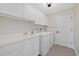 Well-lit laundry room with white cabinets, countertops, sink, washer, dryer, and gray tile floors at 2092 Timucua Trl, Nokomis, FL 34275
