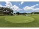 Expansive view of a pristine golf course green with a scenic lake backdrop and lush, mature trees under a bright, partly cloudy sky at 232 Cerromar Way # 38, Venice, FL 34293