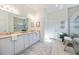 Bright bathroom featuring double sinks, granite counters, a large mirror, decorative art, and a glass-enclosed shower at 23493 Copperleaf Dr, Venice, FL 34293