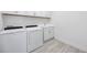 A well-lit laundry room featuring a washer, dryer, sink and cabinet with wood-look tile floors at 23493 Copperleaf Dr, Venice, FL 34293