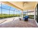 A covered patio features brick flooring and an outdoor seating area with views of the lawn and pool at 23493 Copperleaf Dr, Venice, FL 34293