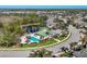 Aerial view of community pool, clubhouse, and winding roads surrounded by lush, mature trees and ponds at 24849 Pennington Ter, Venice, FL 34293