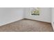 An empty bedroom featuring a large window, carpeted floor, and neutral colors at 24849 Pennington Ter, Venice, FL 34293
