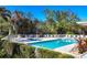 Community pool area featuring lounge chairs and a neatly fenced perimeter, surrounded by manicured green bushes at 24849 Pennington Ter, Venice, FL 34293
