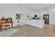 Bright living area flowing into a modern kitchen with white cabinets, countertops, and black appliances at 24849 Pennington Ter, Venice, FL 34293