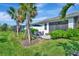 Landscaped backyard featuring a cozy patio area with outdoor seating, lush lawn, and tropical palm trees at 25069 Pearl Lake Cir, Englewood, FL 34223