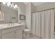 Well-lit bathroom includes a shower with a curtain, a framed sign, and a sink with white cabinetry at 25069 Pearl Lake Cir, Englewood, FL 34223