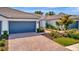 Inviting exterior showcases a brick driveway, attached garage, and manicured landscaping at 25069 Pearl Lake Cir, Englewood, FL 34223