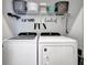 Functional laundry room with modern washer and dryer, a fun decoration, and shelving for supplies at 25069 Pearl Lake Cir, Englewood, FL 34223