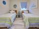 Shared bedroom showcasing matching twin beds with coordinated decor and wood-look floors at 25784 Grayton Ave, Englewood, FL 34223
