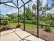 Screened patio with concrete floor offers a view of the lush green backyard at 25784 Grayton Ave, Englewood, FL 34223