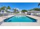 Community pool surrounded by palm trees and a white picket fence on a sunny day at 2614 River Preserve Ct # 2614, Bradenton, FL 34208