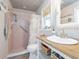 Bright bathroom with a pink shower, white wicker mirror, and beachy decor at 30 Jamestown Ave, Englewood, FL 34223