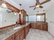 Bathroom with dual sinks, granite countertops, wood cabinetry, and unique glass block window feature at 314 Oakwood Cir, Englewood, FL 34223