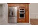 Built-in, stainless steel refrigerator and oven in a kitchen with wooden cabinetry at 314 Oakwood Cir, Englewood, FL 34223