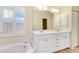 Bathroom featuring double sinks, large mirror, soaking tub and plantation shutters at 429 Riviera St, Venice, FL 34285