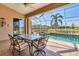 The screened lanai has a dining table and a view of the pool, canal, and lush landscaping at 4403 Via Del Villetti Dr, Venice, FL 34293