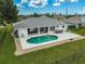 Aerial view of a home featuring a backyard pool with patio and chairs surrounded by a well-maintained lawn at 447 Rotonda Cir, Rotonda West, FL 33947
