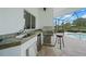 This outdoor kitchen features stainless steel appliances and a sink, all protected within a screened patio near the pool at 4532 Chase Oaks Dr, Sarasota, FL 34241