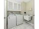 Bright laundry room with washer, dryer, white cabinets and a utility sink at 455 Rubens E Dr, Nokomis, FL 34275