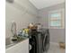 Well-organized laundry room features washer and dryer with sink, storage shelves and marbled tile flooring at 4624 Caribou Ave, North Port, FL 34287