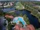 Aerial view of a community pool with lounge chairs surrounded by ponds and a golf course at 515 Sawgrass Bridge Rd, Venice, FL 34292