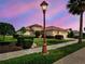 Beautiful home at dusk with a clay tile roof, a three-car garage, and a palm tree next to a sidewalk and street at 515 Sawgrass Bridge Rd, Venice, FL 34292