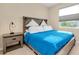 Neutral bedroom features a wooden bed frame, bright blue comforter, and a window for natural light at 5222 Granite Dust Pl, Palmetto, FL 34221