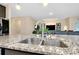 Kitchen island with granite countertop and stainless steel sink, overlooking the cozy living room at 5222 Granite Dust Pl, Palmetto, FL 34221