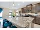 Close-up view of a kitchen island with granite countertops, stainless steel sink, and seating for four at 5222 Granite Dust Pl, Palmetto, FL 34221