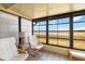 Relaxing sunroom with white cushioned chairs, tiled floor, and large windows providing a scenic view at 5559 Brassy Loop, North Port, FL 34287