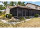 Exterior view of the screened lanai with lush landscaping and a glimpse of the house at 5559 Brassy Loop, North Port, FL 34287