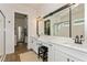 Luxurious bathroom with dual sinks, quartz countertops, and a large mirror, leading to a walk-in closet at 5581 Piccolo St, Nokomis, FL 34275