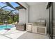 Well-equipped outdoor kitchen featuring a built-in grill and refrigerator, perfect for outdoor entertaining at 5581 Piccolo St, Nokomis, FL 34275