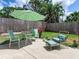 Outdoor patio with stylish seating, a round table, and an umbrella surrounded by lush green landscaping at 607 Bay Point Ave, Nokomis, FL 34275