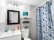 Clean bathroom with a patterned shower curtain, white tile, and a vanity sink with a mirrored cabinet at 607 Bay Point Ave, Nokomis, FL 34275