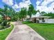 Quaint home exterior with a well-manicured lawn, mature trees, and a charming bench swing for relaxation at 607 Bay Point Ave, Nokomis, FL 34275