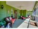 Inviting green porch features cozy seating, ceiling fans, and a charming welcome ambiance at 6293 Taneytown St, North Port, FL 34291