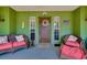 Welcoming green porch with cozy seating, a floral wreath, and a lovely outdoor space at 6293 Taneytown St, North Port, FL 34291