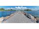 Waterfront view with concrete walkway and stone barriers, showing a path to enjoy serene coastal scenery and blue skies at 710 Ironwood Dr # 165, Venice, FL 34292