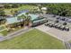 Aerial view of community clubhouse with a parking lot with golf carts near a golf course and pond at 758 Village Cir # 106, Venice, FL 34292