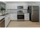 Modern kitchen featuring stainless steel appliances, white cabinets, and granite counters at 758 Village Cir # 106, Venice, FL 34292
