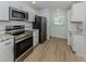 Bright kitchen featuring stainless steel appliances, white cabinets, and wood flooring at 758 Village Cir # 106, Venice, FL 34292
